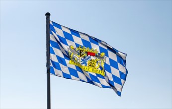 A blue-white flag with the coat of arms of the Free State of Bavaria blows in the wind in Markt Swabia