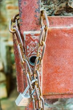 Padlock with iron chain hanging on a door