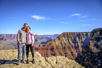 Couple embraces in front of the gigantic gorge of the Grand Canyon