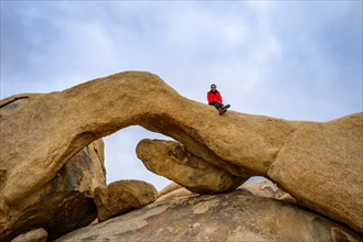 Young woman sits on Arch Rock