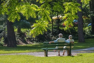 Older couple enjoying spring sun on park bench