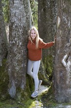 Young woman with long blond hair between trees