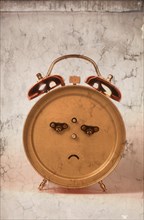 Back of an alarm clock in the shape of a frowning face