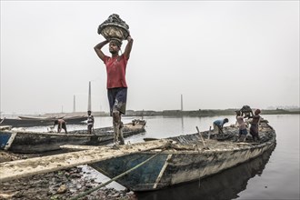 Workers unload clay from a boat