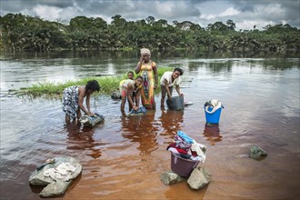 Women washing clothes by the river Ntem in the rainforest