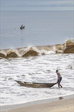 Fisherman with a dugout canoe on the beach
