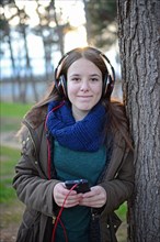 Teenager listening to music with headphones in park
