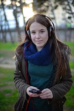 Teenager listening to music with headphones in park