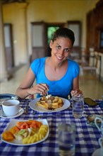 Young woman having breakfast in hotel
