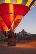 Hot Air balloons at dawn glow with Church Rock in background