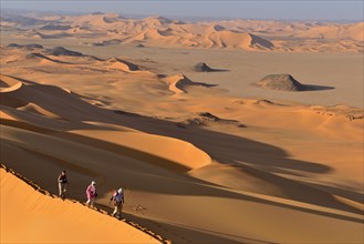 Group of people hiking in the sanddunes of Egedi In Djerane