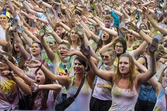 Thousands of young women and man are raising their arms at the colorful Holi festival