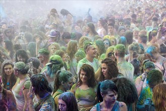 Thousands of young women and man are hardly visible because of color powder in the air at the colorful Holi festival