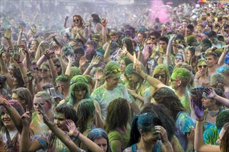 Thousands of young women and man are raising their arms at the colorful Holi festival