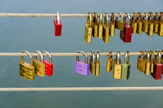 Many colorful locks are locked at a steel cable for a love vow