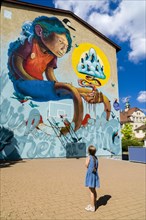 A colorful graffity with comic motive is painted at a house wall