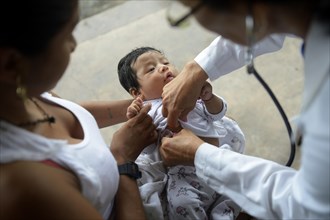 Nurse in a health center examines an indigenous baby