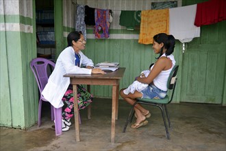 Nurse in health center consults a young indigenous mother