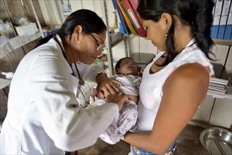 Nurse in a health center examines an indigenous baby