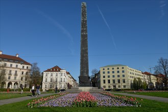 Obelisk with flower beds in front of houses roundabout