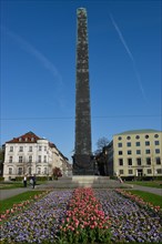 Obelisk with flower bed in front of houses roundabout