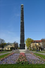 Obelisk with flower bed in front of houses roundabout