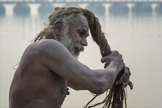 Sadhu drying his dreadlocks on Ganges riverbank