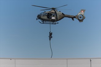 Armed policeman abseiling from helicopter onto roof