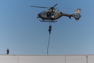 Armed policeman abseiling from helicopter onto roof