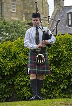 Solo bagpiper playing bagpipes in kilt
