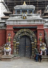 Two Nepalese girls looking at a mobile phone at the gate to Taleju Temple