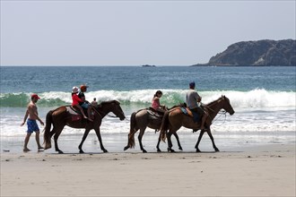 Riders on horseback on the beach Playa Espadilla