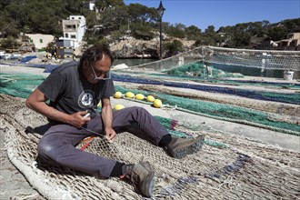 Fishermen repair fishing nets in the port of Cala Figuera