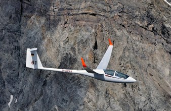 Glider of type ASH25 in front of a rock face in the mountains