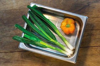 Spring onions and peppers in a colander