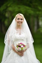Bride in wedding dress with bridal bouquet and veil