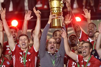 Coach Josep Pep Guardiola lifting the DFB Cup in the air