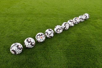 10 footballs adidas Derbystar in a row on grass