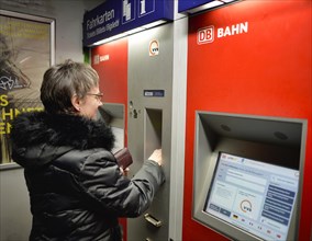 Older woman buys ticket at ticket machine