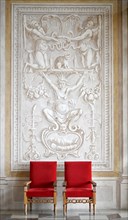 Two red armchairs in front of a wall fresco