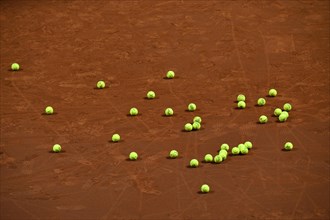 Many tennis balls on clay court