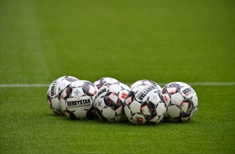 Seven match balls adidas Derbystar lying on grass