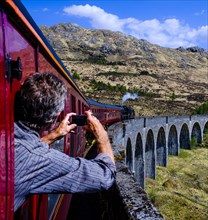 Man leans out the window taking a picture of historic train