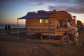 Motorhome in the evening on a pitch by the sea at sunset