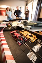 Men playing in the living room with a large Carrera train