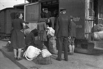 Refugees load their belongings into the freight cars of the tram