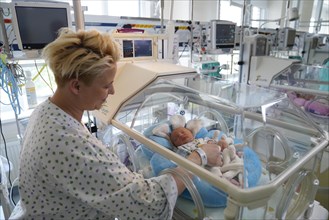 Mother of twins with one of her newborns in an incubator