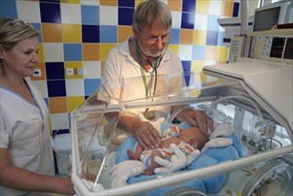 Doctor and nurse examining a newborn in an incubator
