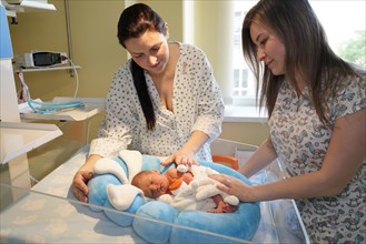 Mother with nurse takes care of newborn in intensive care unit