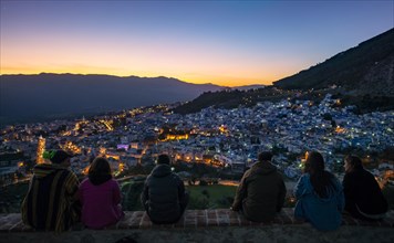 People sitting on a wall overlooking city Chefchaouen